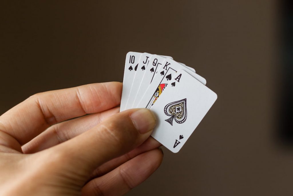 Person holds royal flush in spades on tiny playing cards